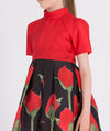 a vibrant red top paired with a playful black skirt adorned with charming red rosebud prints