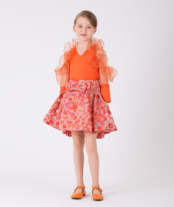 Orange ruffled blouse and orange flared skirt with colorful prints and a bow on the waist